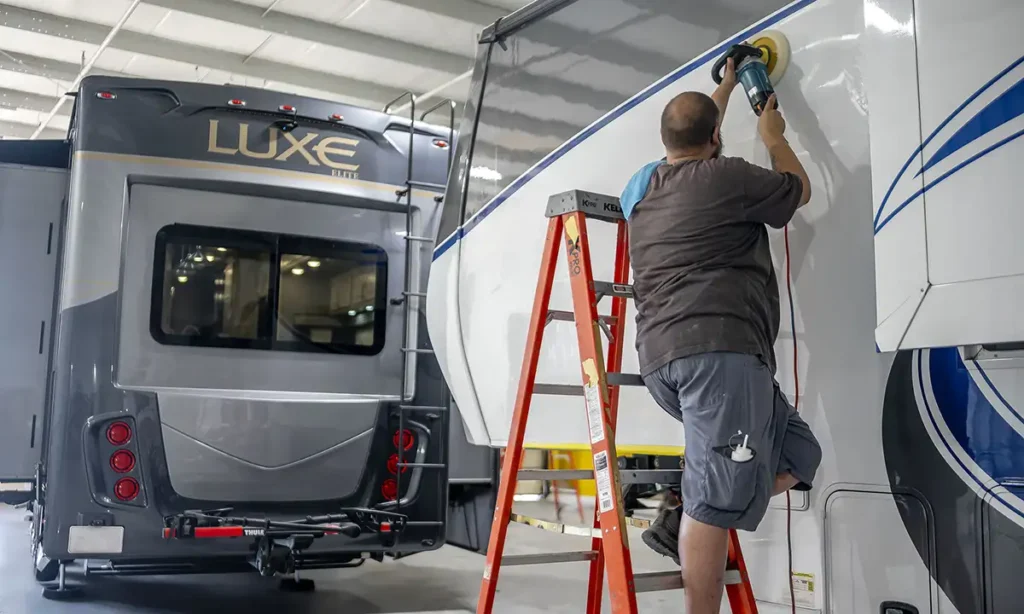 Certified RV Repair technician in Elkhart expertly buffing the exterior sidewall of an RV for a flawless finish.